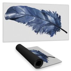 a blue feather on a white background next to a black and silver mouse pad with an image of a blue feather on it