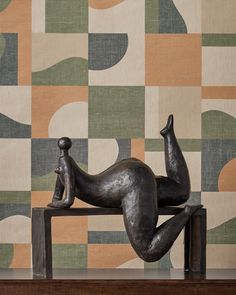 a metal sculpture sitting on top of a wooden table in front of a colorful wall