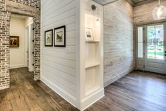 an empty room with wood floors and brick walls, along with pictures on the wall