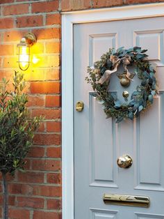 a white door with a wreath on it next to a lamp and potted plant