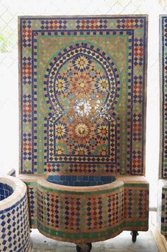 an elaborately designed bathtub sits in front of two mosaic tiles on the wall