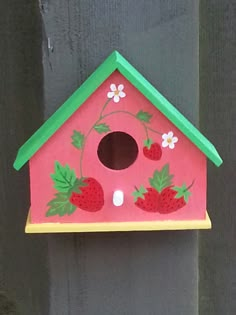 a pink birdhouse with strawberries painted on it