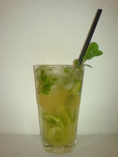 a tall glass filled with lemonade and limes next to a black straw sticking out of it