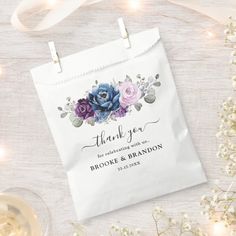 a thank you bag with flowers on it next to wine glasses and baby's breath