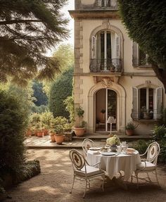 an outdoor dining table in front of a large house