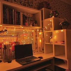 a laptop computer sitting on top of a desk next to a book shelf filled with books