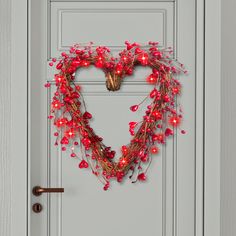 a heart shaped wreath with red lights on the front door