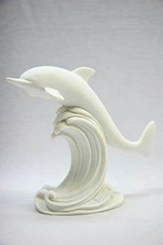 a white ceramic sculpture of a dolphin on a wave