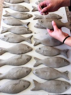 a person is making fish sculptures out of clay