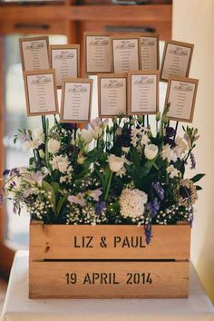 there is a wooden box with flowers in it and seating cards on the top shelf