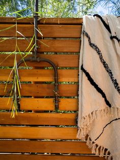 a towel is hanging on the side of a wooden bench next to a tree branch