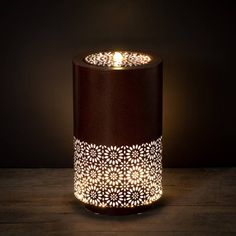 a lit candle sitting on top of a wooden table next to a dark wall and floor