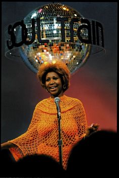 a woman standing in front of a microphone and disco ball on top of her head