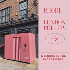 a pink fridge sitting on the side of a road next to a building with windows