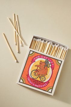 matches are arranged in an open box on a white surface with orange and pink background