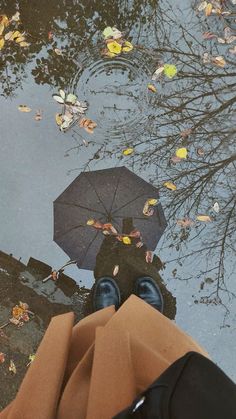 a person standing in front of a puddle with an umbrella over their head and feet on the ground