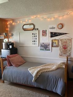 a small bedroom with a bed, desk and pictures on the wall above it's headboard