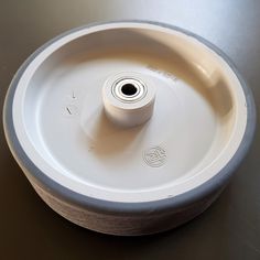 a white plastic wheel on a table with a black top and bottom part in the center