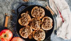 apples and cinnamon rolls sitting in a pan on top of a table next to an apple