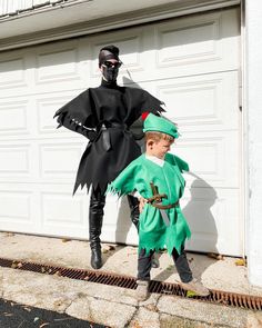 two children dressed up as batman and robin wayne in front of a garage door,