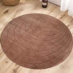 a brown round rug on the floor in a room with wooden floors and white walls