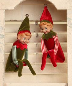 two elf dolls sitting on top of a shelf