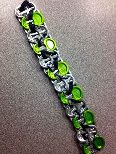 a green and black bracelet with lots of buttons on it's side, sitting on a table