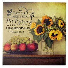 a vase filled with sunflowers and fruit on top of a wooden table next to a sign that says let us come into his presence with thanksgiving