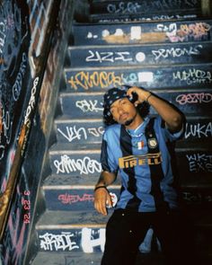 a young man standing on top of a set of stairs next to graffiti covered steps