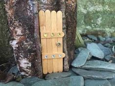 a wooden door sitting on top of a pile of rocks next to a tree trunk