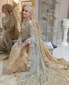 a woman sitting in front of a mirror wearing a bridal gown and veil with sequins on it