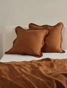 two brown pillows sitting on top of a bed