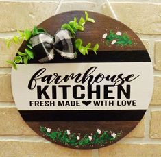 a sign that says farmhouse kitchen fresh made with love hanging on a wall next to a brick wall