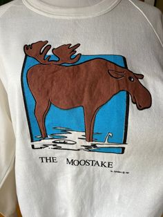 Add a little fun to a comfy outfit with this novelty graphic crewneck sweater featuring "The Moostake" moose cartoon by Vic Anonsen, dated 1987 Label: unknown Made in Canada Size: Extra Large Measurements (taken flat): Pit to pit - 22.5" Hem - 16" Shoulder to hem - 27" Pit to hem - 17" Great vintage condition - there are a few small stain dots but the fleece feels unworn Feel free to message me for more measurements, pictures, or to ask any other questions you might have! Please see my shop policies regarding shipping. Standard shipping does not include tracking. Vintage Cotton Sweatshirt With Graphic Print, Retro Sweatshirt With Screen Print For Loungewear, Retro Screen Print Sweatshirt For Loungewear, Retro Cotton Sweatshirt With Funny Print, Vintage Long Sleeve Sweatshirt With Graphic Print, Retro Cotton Sweatshirt With Graphic Print, Vintage Screen Print Tops For Winter, Vintage Long Sleeve T-shirt For Loungewear, Vintage White Sweatshirt With Graphic Print