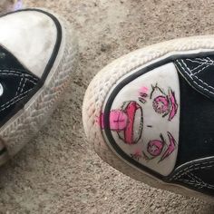 someone has painted their tennis shoes with pink and white designs on them, while they are standing on the ground