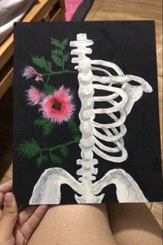 someone is holding up a skeleton and flower painting on canvases that they are painted