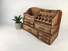 a wooden box with drawers next to a potted plant