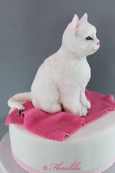 a white cat sitting on top of a cake