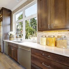 a kitchen filled with lots of wooden cabinets and white counter tops next to a window