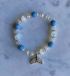 "Genuine gemstone bracelet - limited quantity, will not have any more available after this. Custom, handmade bracelet with round blue aquamarine beads, round white selenite beads, and smaller, faceted clear quartz beads. Silver-toned accents and a little mermaid tail dangle charm.  Bracelet can stretch to fit your wrist. In its \"resting,\" unstretched state, it is around 7.5 inches in circumference. Length is around 8 inches. Thickness of round beads is about 1/3 of an inch. \"Aquamarine helps us to gain insight, truth, and wisdom. It can be used to help calm the mind, nerves, and anxieties. Physically, it's said to help relieve the symptoms of fluid retention. Because it's associated with water and water is cleansing, aquamarine can also help aid in the flushing of toxins from the body.\ Blue Moonstone Beaded Bracelets With Gemstone Beads, Handmade Blue Moonstone Beaded Bracelets, Handmade Blue Moonstone Bracelets, Blue Moonstone Beaded Bracelets Gift, Gift Blue Moonstone Beaded Bracelets, Blue Moonstone Bracelets For Healing, Blue Moonstone Bracelet For Healing, Date Bracelet, Aquamarine Bracelet