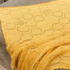 a yellow crocheted blanket sitting on top of a couch next to a pillow