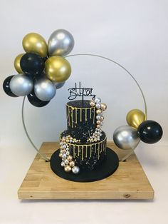 a black and gold birthday cake with balloons