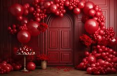 a bunch of balloons that are in front of a red wall with flowers and a cake