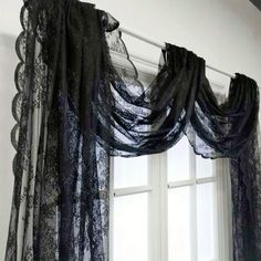 an open window with black lace curtains hanging from it's side and the curtain is closed