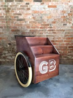 an old fashioned wooden cart with wheels on concrete floor in front of brick wall,