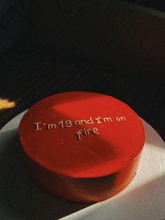 a red cake with writing on it sitting on a white plate next to a banana