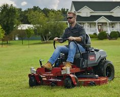 a man riding on the back of a red lawn mower