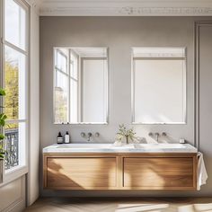 a bathroom with two sinks and mirrors on the wall next to each other in front of large windows