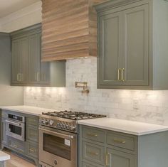 a kitchen with green cabinets and white counter tops, gold trim on the oven hood