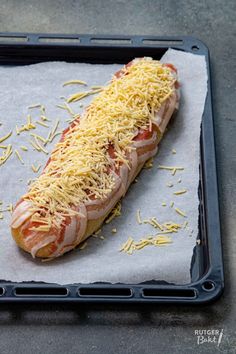 a hot dog covered in cheese on top of a pan with other food items around it